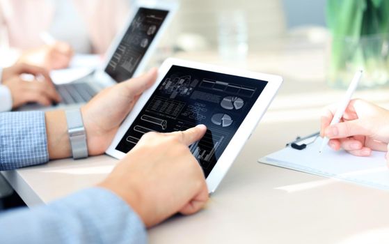 business documents on office table with smart phone and laptop computer and graph business with social network diagram and three colleagues discussing data in the background