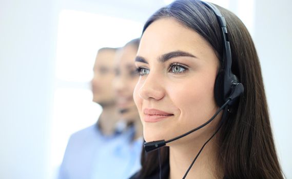 Smiling female call centre operator doing her job with a headset while looking at camera