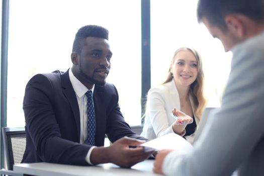 Business people in discussing something while sitting together at the table.