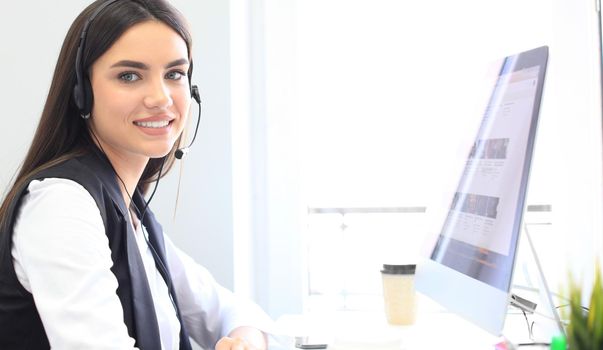 Businesswoman wearing microphone headset using computer in the office - operator, call center.