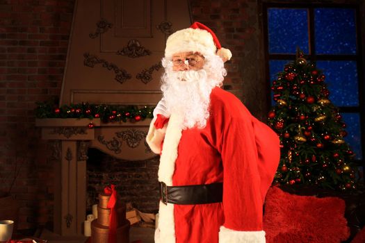 Santa Claus holding carrying sack with gifts for kids.