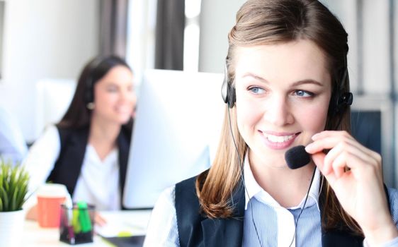 Businesswoman wearing microphone headset using computer in the office - operator, call center.