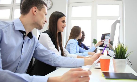 Team of colleagues brainstorming together while working on the computer