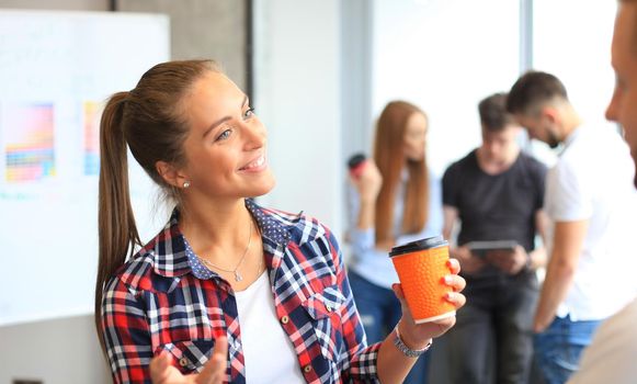 Portrait of a happy casual businesswoman standing at her workplace in office