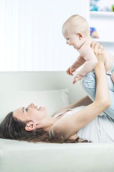 happy young mother playing with cute one year old baby in the room for children
