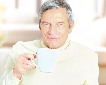 Portrait of senior man holding coffee mug, smiling at camera