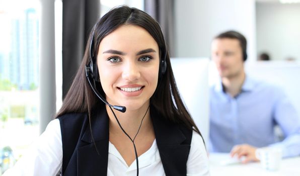 Businesswoman wearing microphone headset using computer in the office - operator, call center.