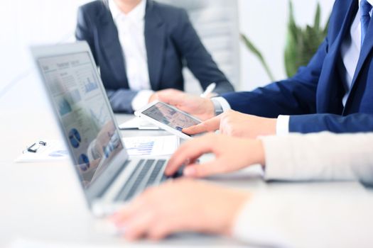 business documents on office table with smart phone and laptop computer and graph business with social network diagram and three colleagues discussing data in the background