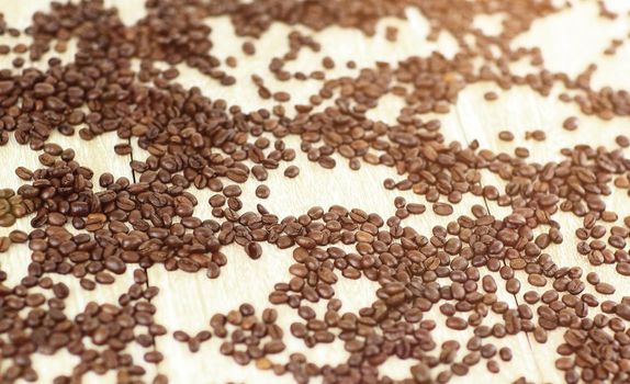 close-up of black coffee beans scattered on a wooden table.background.