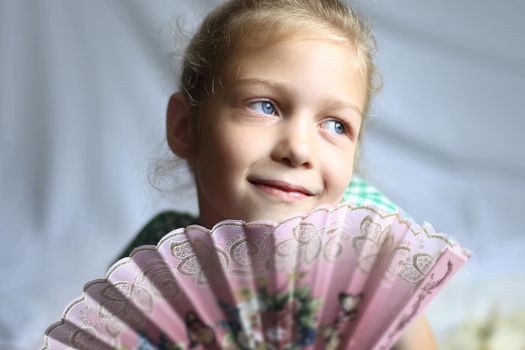 portrait - cute on bright background little girl with a fan .the photo has a empty space for your text