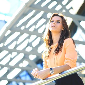 Portrait of a young woman who is considering a work plan on the background of business building