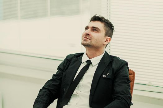 successful businessman with smartphone sitting in a chair in a modern office .the photo has a empty space for your text