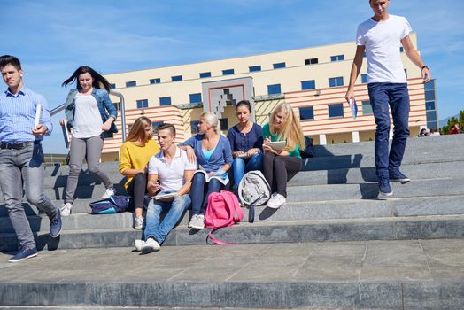 Group portrait  of happy  students outside sitting on steps have fun