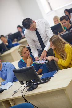 group of students with teacher in computer lab classrom learrning lessons,  get help and support