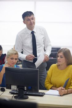 group of students with teacher in computer lab classrom learrning lessons,  get help and support