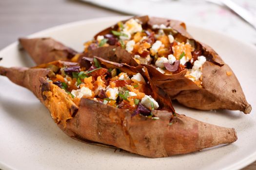 Baked sweet potato stuffed with chopped sun-dried tomatoes, olives, feta cheese and basil with aromatic dressing