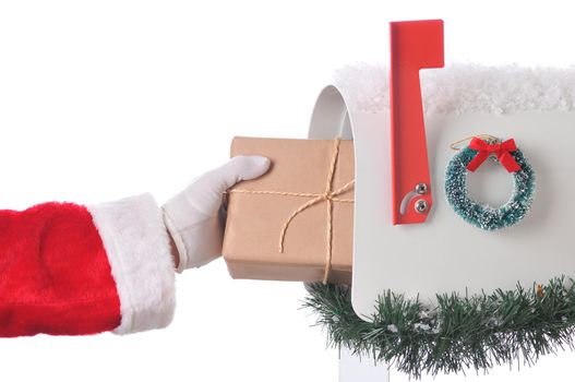 Closeup of Santa Claus placing package in a mailbox that is decorated for Christmas with wreath, snow and garland. Horizontal format isolated on white.