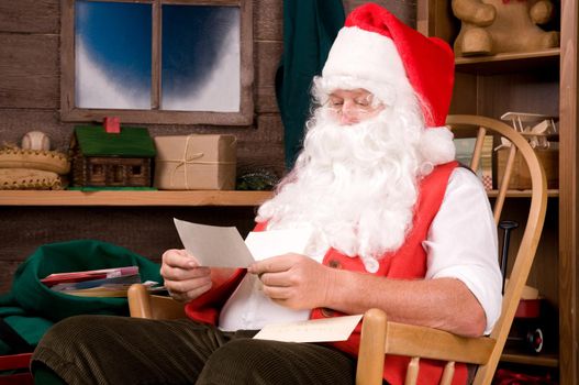 Santa Claus Sitting in His Workshop reading a letter. Horizontal Composition.