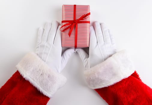 High angle shot of Santa Claus hands with a red and white striped Christmas Present.