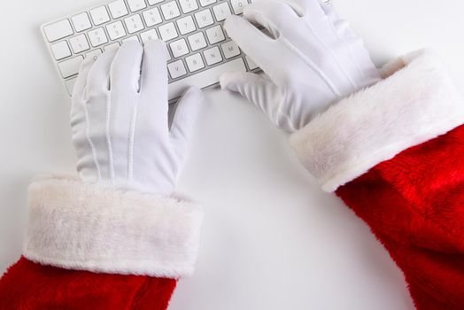 High angle closeup of Santa Claus hands using his computer keyboard.