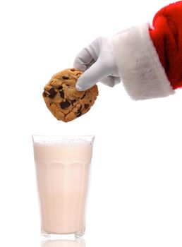 Santa Claus about to dunk a chocolate chip cookie into a glass of milk over a white background