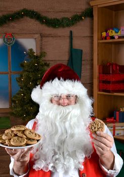 Santa Claus in his workshop with a plate of fresh baked cookies.