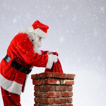 Closeup of Santa Claus placing his bag of toys into a chimney while it snows on Christmas Eve.