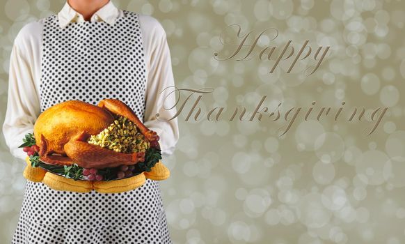 Woman holding a Thanksgiving turkey on a platter over a warm bokeh background, with Happy Thanksgiving and copy space.