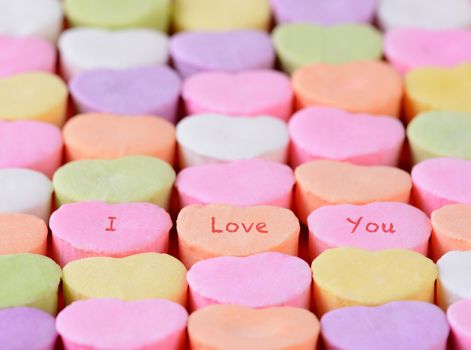 Closeup of the words I Love You spelled out on candy hearts.  The hearts are arranged in straight rows only candies have words. Shallow depth of field. Great for Valentine's Day projects.
