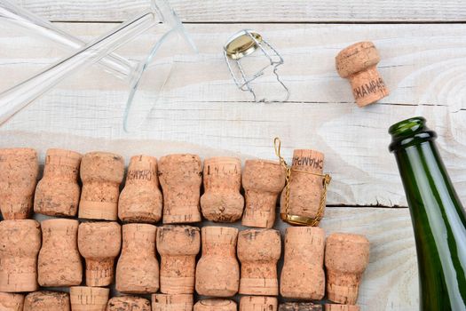 HIgh angle shot of a empty champagne bottle with corks and two flutes. Closeup on a rustic white wood table. Horizontal format.