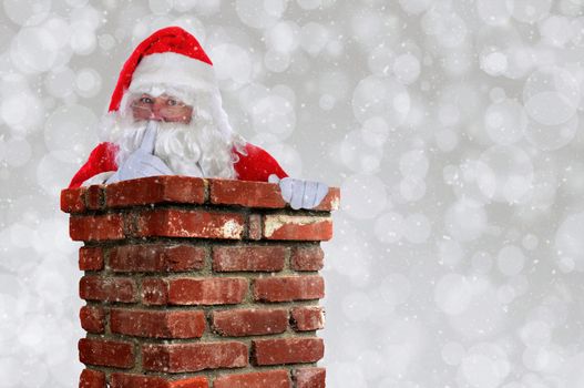 Santa Claus Going Down Chimney making Shh sign with finger to lips. Horizontal with silver bokeh background and snow effect and copy space.