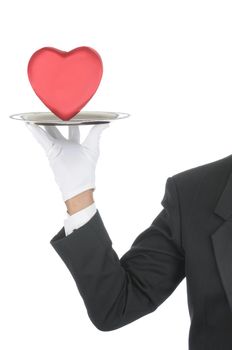 Butler wearing tuxedo and formal gloves holding a heart shaped box on a silver tray. Shoulder hand and arm only isolated on white vertical composition.