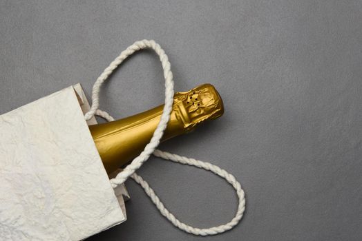Champagne: Gift Bag with a bottle of sparkling wine on gray tile surface.