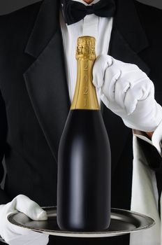 Closeup of a Sommelier holding a Champagne bottle, dated 2021 for the New Year on a silver tray. Man is unrecognizable, Vertical Format.