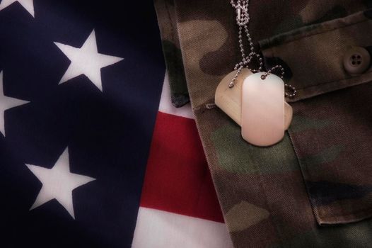 USA military Dog Tags on Camouflage fatigues and American Flag