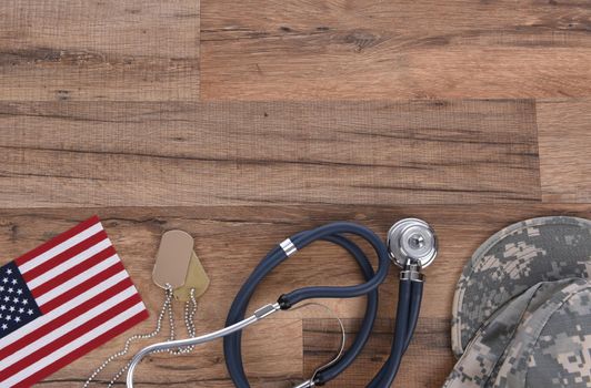 Military Health Care Concept. Camo hat, dog tags, stethoscope, pills, and American Flags on a wood background. 