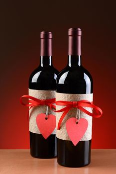 Closeup of a wine bottles decorated for Valentines Day. Both bottles have a red ribbon and heart shaped tag and a blank label. Vertical Format.