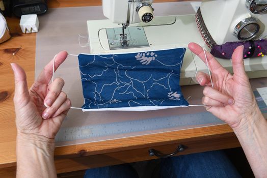 Closeup of a woman’s hands holding an almost finished homemade COVID-19 face mask, to ease the shortage of available protection for the public.