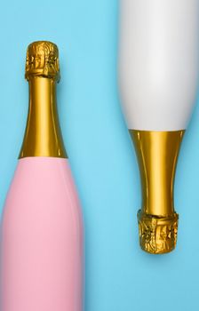 A Pink and a White Champagne bottle on a blue teal background. Vertical High angle shot. 