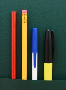 An assortment of pencils and pens in the pocket of a binder. 