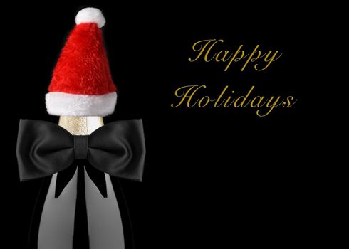 Closeup of a Champagne Bottle with Black Bow Tie and Santa Hat isolated on black background with Happy Holidays