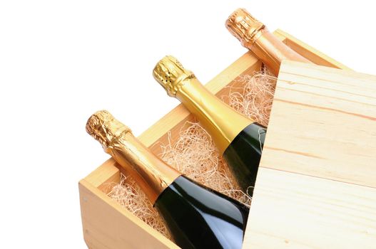 Closeup of three Champagne bottles on their side in a wooden crate. Crate lid is pulled partially back exposing the bottles and packing excelsior. Horizontal format isolated on white.