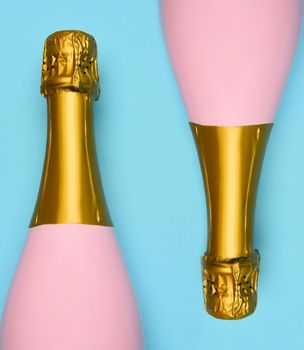 Two Pink Champagne bottles on a blue teal background. Horizontal high angle shot.