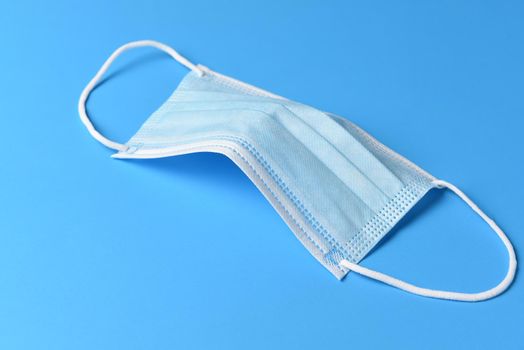 PPE Covid-19 pandemic concept. A surgical mask on a blue background.