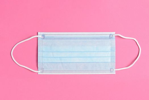 Blue Surgical Mask on a Pink Background, High angle view.