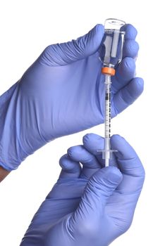 Two hands with a syringe and vial of Covid-19 vaccine over a white background.