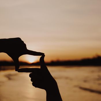 Woman hands place together like praying from nature in front of sunset beach background.