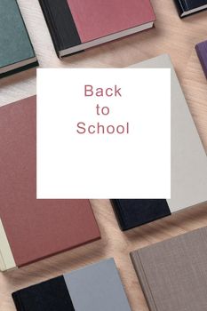 Back to School Concept: Closeup of school books on a wood desk with an overlay copy space square with the words Back to School. Text can easily be changed to suit your needs.