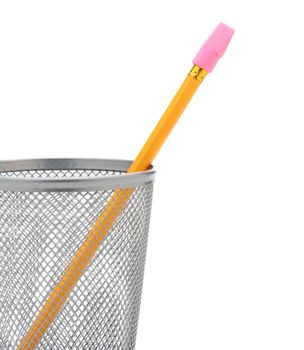 Closeup of a single pencil in a wire pencil cup isolated on white. The yellow pencil has a stick on pink eraser and is at an angle. 