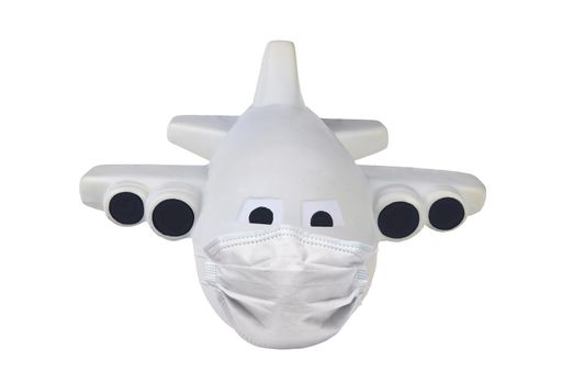 Covid-19 and travel restrictions concept. Toy Airplane with a surgical mask isolated on whte.